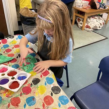 A girl finger painting in the classroom