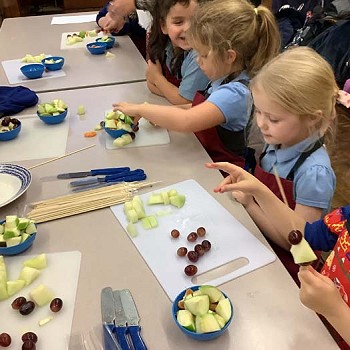 Children making fruit kebab in the cookery clubs