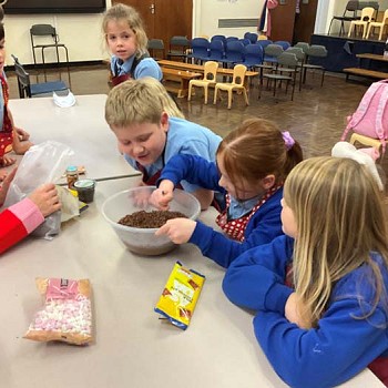 Children watching another child mixing ingreadients in the cookery club