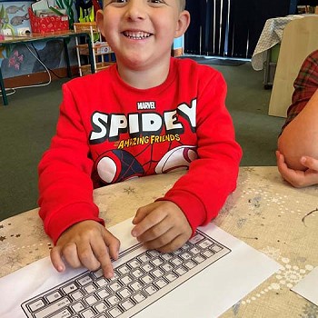 Plentyn yn gwenu wrth gymryd rhan mewn clwb digidol